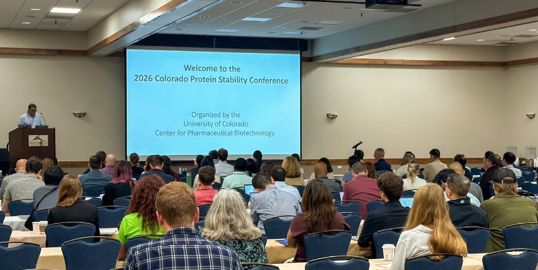 Audience seated in a conference room facing a presentation screen welcoming attendees to the 2026 Colorado Protein Stability Conference, organized by the University of Colorado Center for Pharmaceutical Biotechnology.