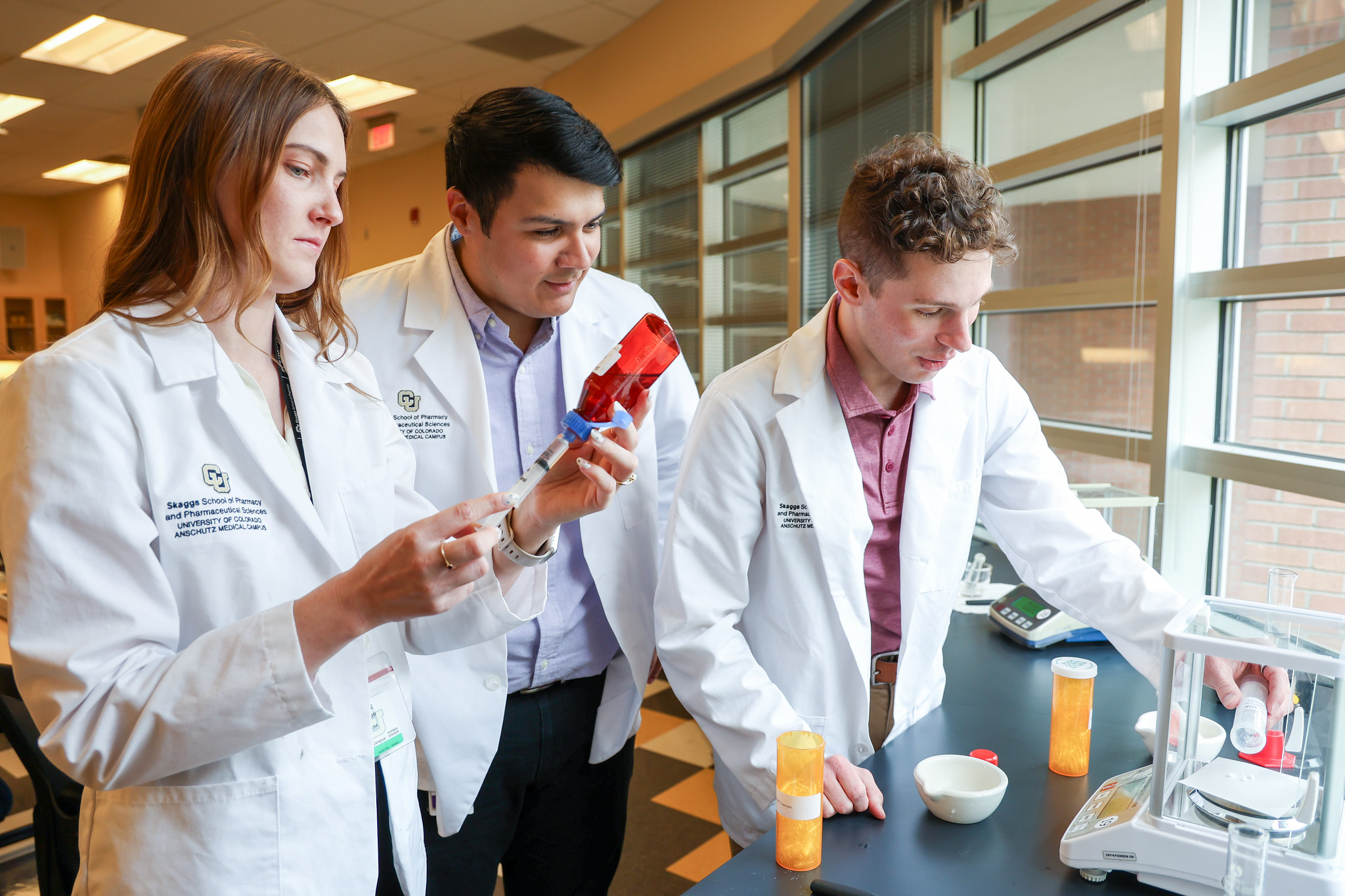 Students in white coats looking at microscrope