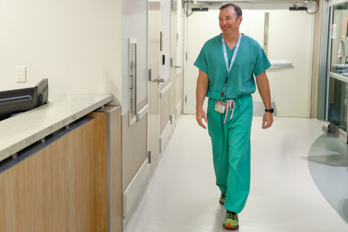 Man in scrubs walking in hospital hallway