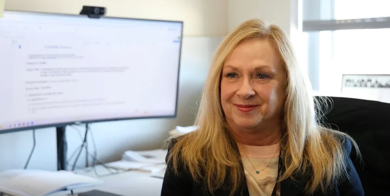 Blonde woman in front of computer smiling