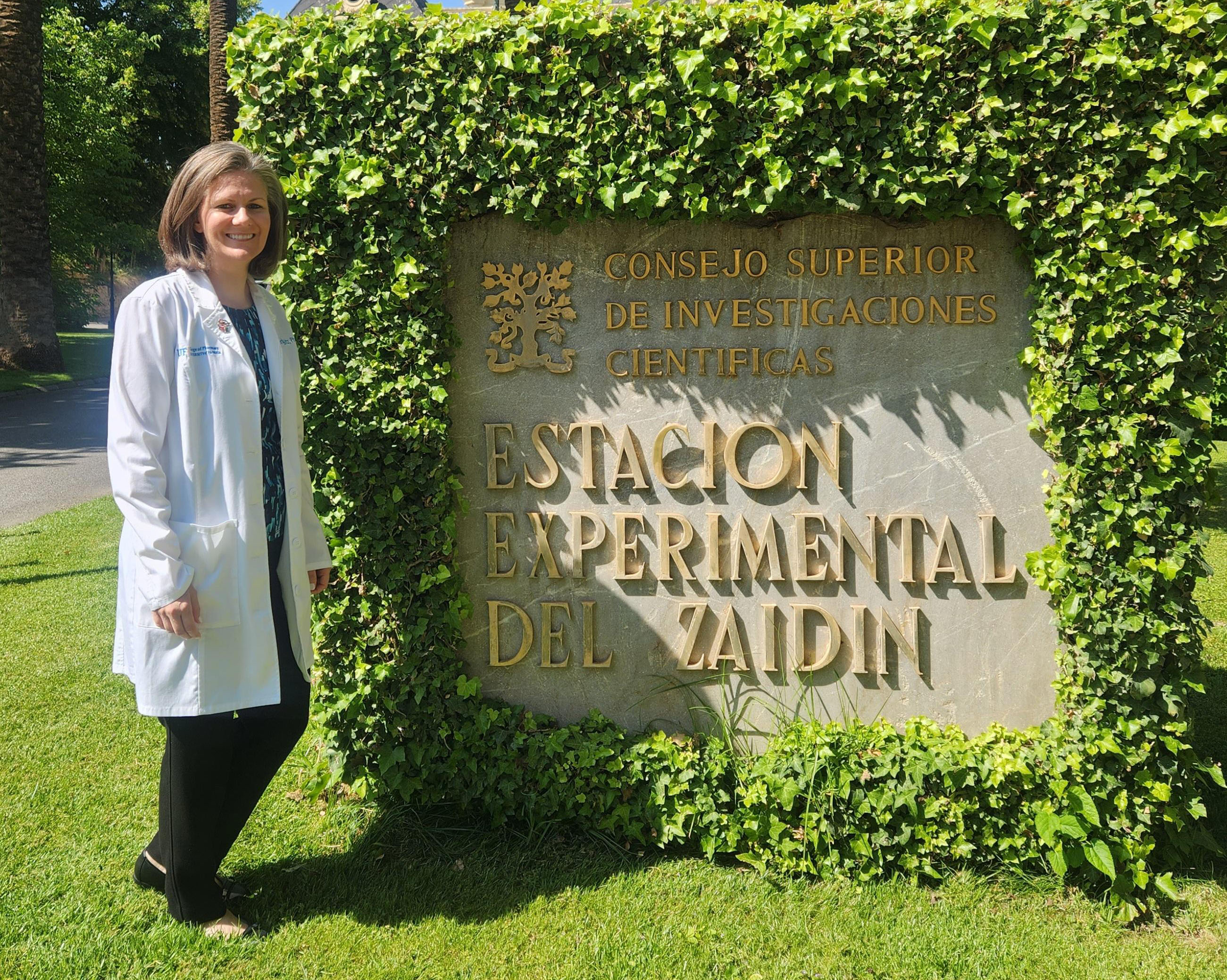 Woman with white coat standing in front of Estacion Experimental Del Zaidin sign
