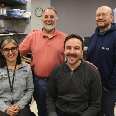 Group of 3 men and 1 woman in a lab.