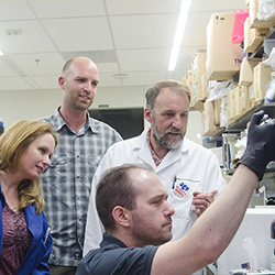 Group of faculty and students looking at test tube.