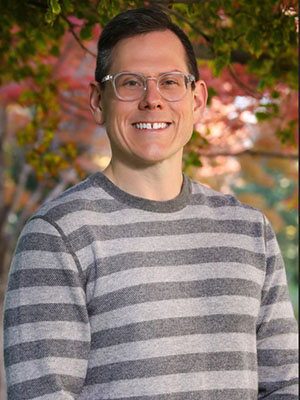 man with brown hair and striped shirt headshot